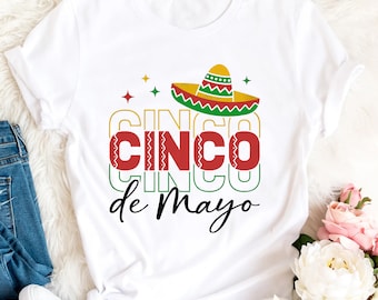 May include: White t-shirt with a colorful graphic design that says "Cinco de Mayo" with a sombrero on top.