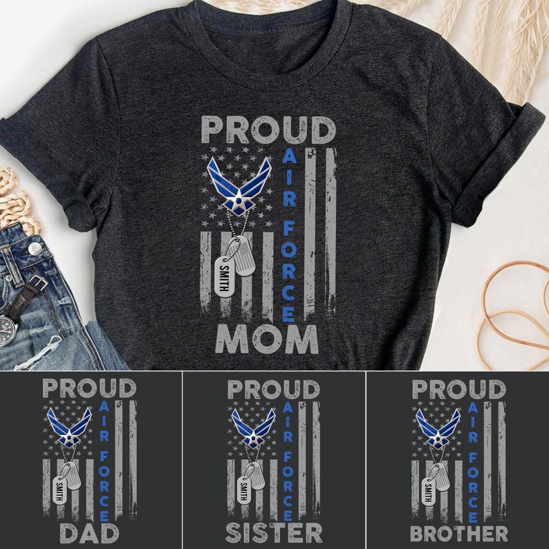 Pu&ograve; includere: T-shirt grigio scuro con un design patriottico. Il design include le parole "PROUD AIR FORCE MOM" in bianco e blu, insieme a un emblema dell'Air Force e targhette identificative. La maglietta ha un design a bandiera usurata.