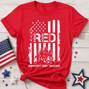 Könnte beinhalten: Ein leuchtend rotes Kurzarm-T-Shirt mit einer weißen Grafik einer abgenutzten amerikanischen Flagge, vier Soldaten und dem Text REMEMBER EVERYONE DEPLOYED sowie SUPPORT OUR TROOPS in fetter, weißer Schrift auf der Vorderseite.