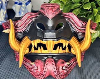 May include: A red and black samurai mask with gold teeth and intricate details. The mask is made of plastic and has a 3D printed look.