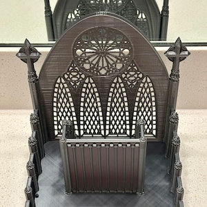 Puede incluir: Un objeto decorativo de estilo gótico catedral impreso en 3D con un diseño detallado. El objeto presenta un arco apuntado, vidrieras y un pequeño espacio interior.