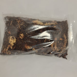 May include: A clear plastic bag filled with dark brown and light brown dried plant material.