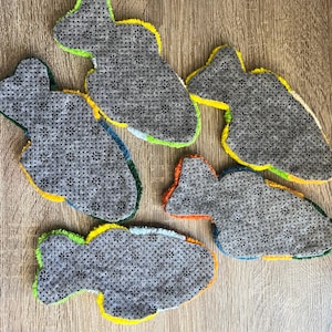 K&ouml;nnte beinhalten: F&uuml;nf fischf&ouml;rmige Teppiche mit grauem, strukturiertem Untergrund. Die Teppiche haben helle Zierleisten in Gelb, Gr&uuml;n, Blau und Orange. Sie sind auf einer Holzoberfl&auml;che angeordnet. Ideal f&uuml;r Kinderzimmer.
