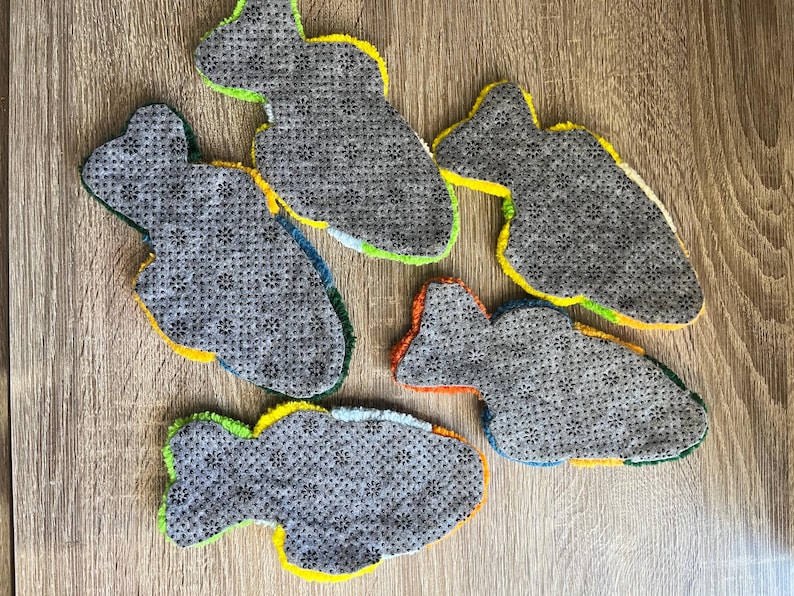 K&ouml;nnte beinhalten: F&uuml;nf fischf&ouml;rmige Teppiche mit grauem, strukturiertem Untergrund. Die Teppiche haben helle Zierleisten in Gelb, Gr&uuml;n, Blau und Orange. Sie sind auf einer Holzoberfl&auml;che angeordnet. Ideal f&uuml;r Kinderzimmer.