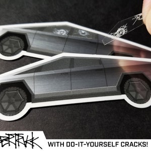 May include: Two silver Cybertruck stickers with a clear sheet of 'cracks' that can be applied to the stickers. The text 'WITH DO-IT-YOURSELF CRACKS!' is below the stickers.