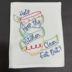 May include: White kitchen towel with embroidered colorful bowls and the text "Help Keep the Kitchen Clean Eat Out!"