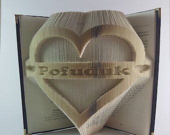 Puede incluir: Una escultura de arte de libro en forma de corazón con la palabra "Posudnik" escrita en una pancarta debajo del corazón.