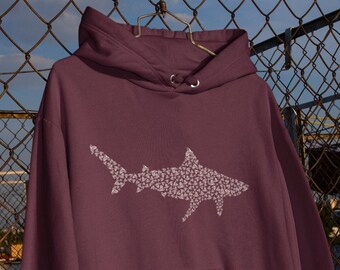 Puede incluir: Una sudadera con capucha color marrón con un gráfico de tiburón blanco hecho de pequeñas formas blancas. La sudadera tiene un bolsillo canguro y una capucha con cordón.