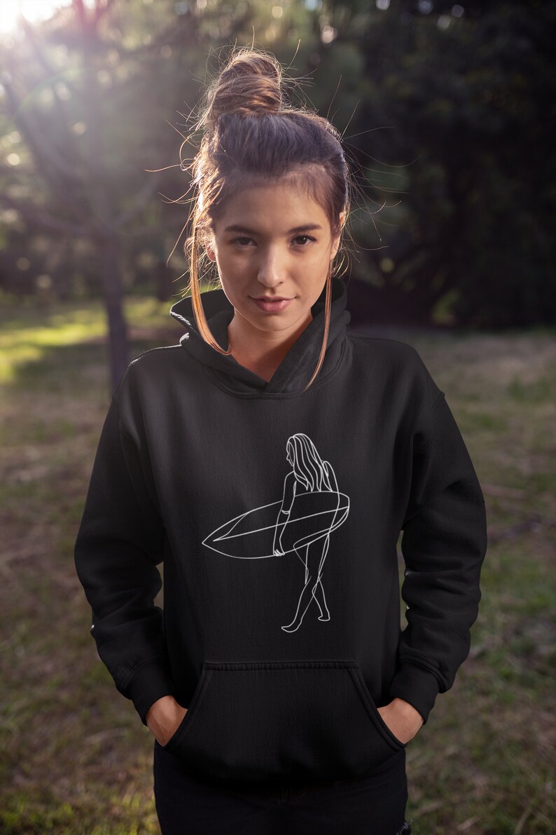May include: Black hoodie with a white line drawing of a woman surfing. The woman is facing away from the viewer and is holding a surfboard.