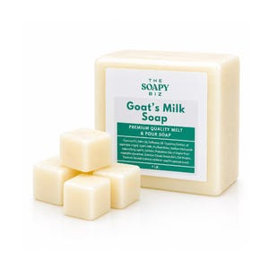 Puede incluir: Un bloque de jabón de leche de cabra de The Soapy Biz, con una etiqueta que detalla los ingredientes. Varios cubos de jabón cuadrados pequeños están frente al bloque más grande. La etiqueta dice "Premium Quality Melt & Pour Soap" y enumera los ingredientes.