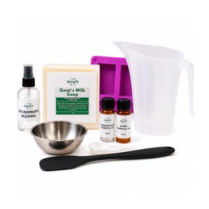 May include: A collection of soap-making supplies, including a bar of Goat's Milk Soap, essential oils, a purple mold, a mixing bowl, a spatula, a measuring cup, and a bottle of 91% isopropyl alcohol. The essential oils are labeled Frankincense and Myrrh.