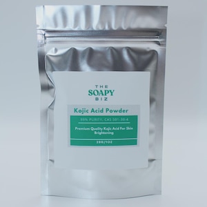 Może przedstawiać: Srebrna torebka z Kojic Acid Powder od The Soapy Biz. Biała etykieta zawiera nazwę produktu, czystość i szczegóły dotyczące rozjaśniania skóry. Torebka zawiera 28 gramów proszku.