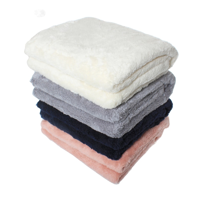 May include: A stack of five plush blankets in different colors. The top blanket is white, followed by gray, navy blue, and pink.