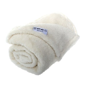 May include: A cream-colored, soft, plush pet blanket rolled up. The blanket has a small white label with the text "pet wiz" and the website "www.petwiz.co.uk".