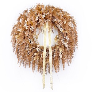 May include: A brown and cream dried floral wreath with a beige velvet ribbon.