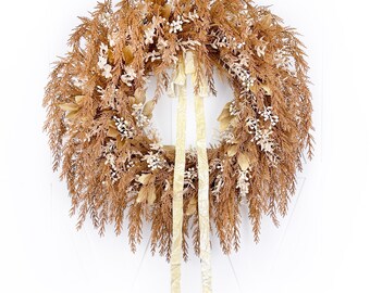 May include: A brown and cream dried floral wreath with a beige velvet ribbon.