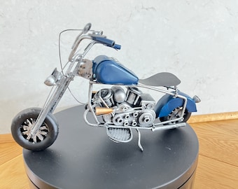 May include: A blue and silver metal motorcycle figurine. The motorcycle has a detailed engine and a black seat.