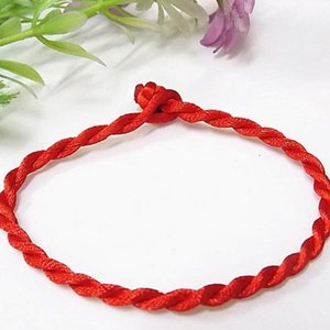 May include: A red braided string bracelet, tied in a knot at the end.