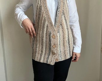 May include: A striped knitted vest with a V-neck and button closure. The vest is made of a soft, cozy material and has a relaxed fit.