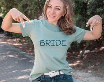 May include: A light green t-shirt with the word "BRIDE" printed in dark blue with small hearts on either side of the letters.