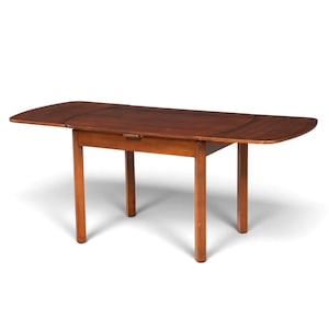 Peut inclure: Une table à manger rectangulaire en bois avec une finition brun riche et des coins arrondis. La table dispose de deux rallonges latérales extensibles actuellement déployées, soutenues par un cadre robuste avec quatre pieds droits.