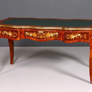 Könnte beinhalten: Ein antiker Schreibtisch mit einer dunkelgrünen Lederoberfläche und drei Schubladen. Der Schreibtisch ist aus Holz mit rotbraunem Finish, goldenen Akzenten und floralen Intarsien gefertigt. Die Beine sind geschwungen.