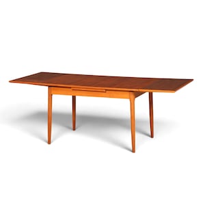 Op de afbeelding: Een rechthoekige houten eettafel met een warme bruine afwerking, voorzien van vier taps toelopende poten en twee uitschuifbare zijbladen die gedeeltelijk zijn uitgetrokken om het tafeloppervlak te vergroten voor extra zitruimte.