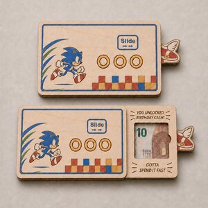 May include: Two rectangular wooden money holders featuring a printed graphic of Sonic the Hedgehog running past gold rings and colorful blocks. The design includes the text Slide, You Unlocked Birthday Cash, and Gotta Spend It Fast.