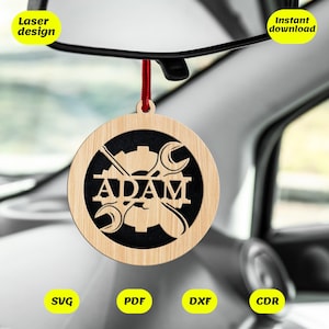 Puede incluir: Adorno de coche de madera con el nombre "ADAM" recortado, con un diseño de engranaje y llave inglesa. Cuelga de una cuerda roja y se muestra en el interior de un coche. También se ven las palabras "Laser design" e "Instant download".