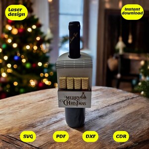 Può includere: Un porta bottiglie di vino in legno tagliato al laser con una fessura per una bottiglia e uno spazio per i cioccolatini. Il porta bottiglie è decorato con il testo "Merry Christmas" e un piccolo albero di Natale. Il porta bottiglie è mostrato su un tavolo di legno con un albero di Natale sullo sfondo.
