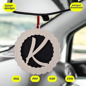 May include: A wooden car air freshener with a laser cut design of the letter K. The air freshener is hanging from a rear view mirror in a car. The air freshener is available in SVG, PDF, DXF, and CDR formats. Instant download.