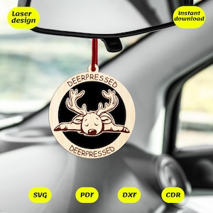 May include: A wooden Christmas ornament with a deer lying down and the text "DEERPRESSED" on a black background. The ornament is hanging from a red string in a car.