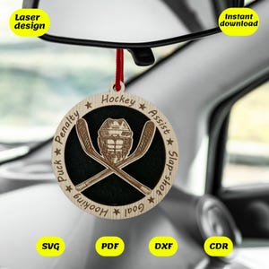May include: A wooden hockey ornament with a black background and a hockey mask and sticks. The ornament has the words "Hockey", "Assist", "Slap-shot", "Goal", "Hooking", "Puck", and "Penalty" around the edge.