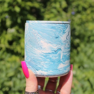 Op de afbeelding: Een blauwe en witte marmeren keramische container met een gladde, afgeronde vorm. De container is ongeveer 10 cm hoog en 7,5 cm breed.