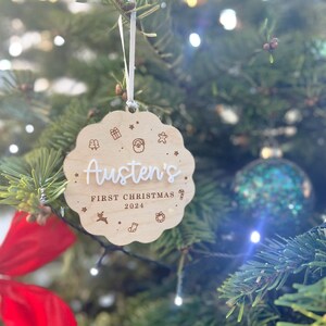 May include: A wooden Christmas ornament with the text "Austen's First Christmas 2024" and various holiday icons.