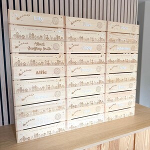 May include: A stack of light-colored wooden crates, each featuring a laser-engraved winter village scene, a silhouette of a sleigh with reindeer, and the text A SPECIAL CHRISTMAS DELIVERY. Each crate is personalized with a unique name.