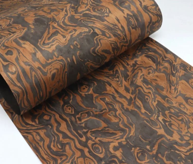 May include: A sheet of wood veneer with a brown and black marbled pattern. The wood has a unique and intricate grain.