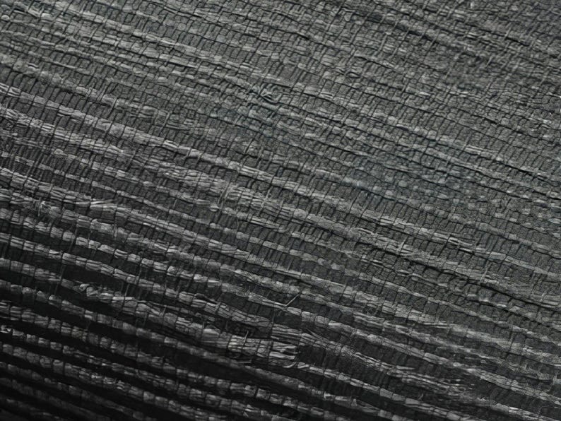 May include: Close-up of a black woven fabric with a textured surface. The fabric has a grid-like pattern and appears to be made of natural fibers.