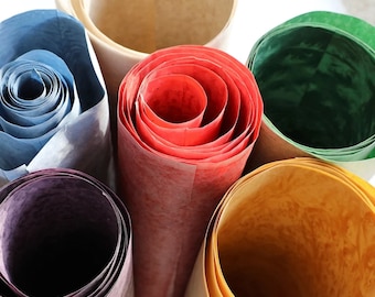 May include: Six rolled up pieces of paper in different colors, including blue, red, green, yellow, and brown. The paper is textured and has a natural look.