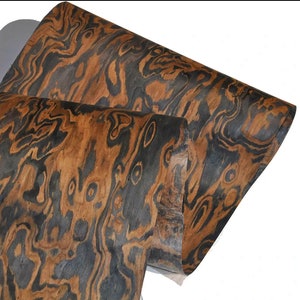 May include: A sheet of wood veneer with a unique black and brown wood grain pattern. The wood has a swirling, marbled appearance.