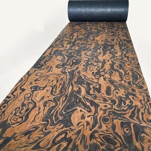 May include: A roll of wood veneer with a black and brown swirling pattern. The veneer is rolled up and has a black backing.
