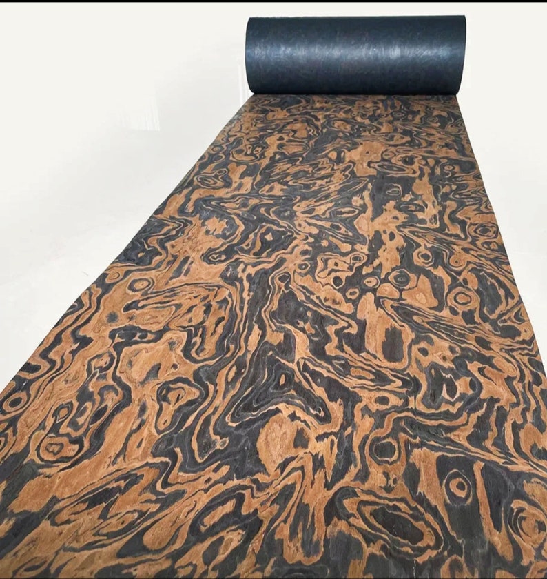 May include: A roll of wood veneer with a black and brown swirling pattern. The veneer is rolled up and has a black backing.