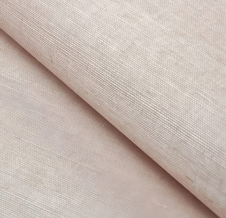 Puede incluir: Primer plano de una tela texturizada de color rosa claro con un brillo sutil. La tela tiene un patr&oacute;n tejido y una sensaci&oacute;n suave y lisa.