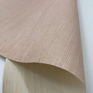 Puede incluir: Primer plano de una tela tejida de color marr&oacute;n claro con una textura sutil. La tela est&aacute; doblada, revelando un lado inferior beige m&aacute;s claro.