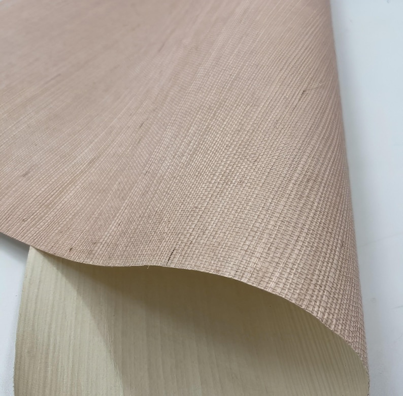 Puede incluir: Primer plano de una tela tejida de color marr&oacute;n claro con una textura sutil. La tela est&aacute; doblada, revelando un lado inferior beige m&aacute;s claro.