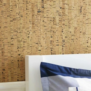 May include: A close-up of a cork wall with a white headboard and a blue and white patterned pillow. The cork wall has a natural, rustic look.