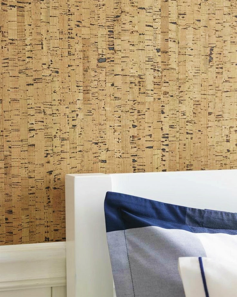 May include: A close-up of a cork wall with a white headboard and a blue and white patterned pillow. The cork wall has a natural, rustic look.