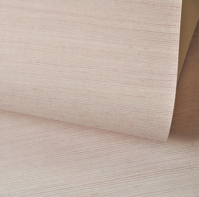 Puede incluir: Primer plano de una tela tejida de color rosa p&aacute;lido con una textura sutil. La tela est&aacute; doblada, revelando un tono de rosa m&aacute;s claro debajo.