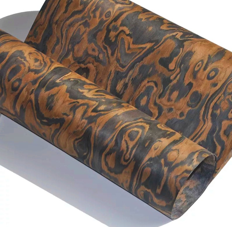 May include: A sheet of wood veneer with a distinctive brown and black wood grain pattern. The veneer is rolled up and has a natural, organic look.