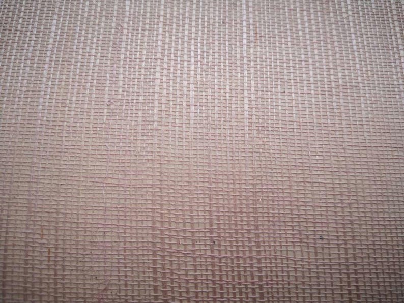 Puede incluir: Primer plano de una tela tejida de color marr&oacute;n claro y textura sutil. La tela tiene un patr&oacute;n de cuadr&iacute;cula creado por el proceso de tejido.